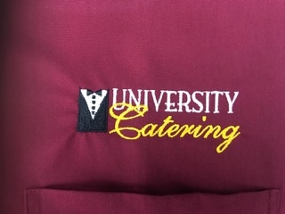 University Catering Maroon garment with embroidered University Catering logo in white, black and yellow.